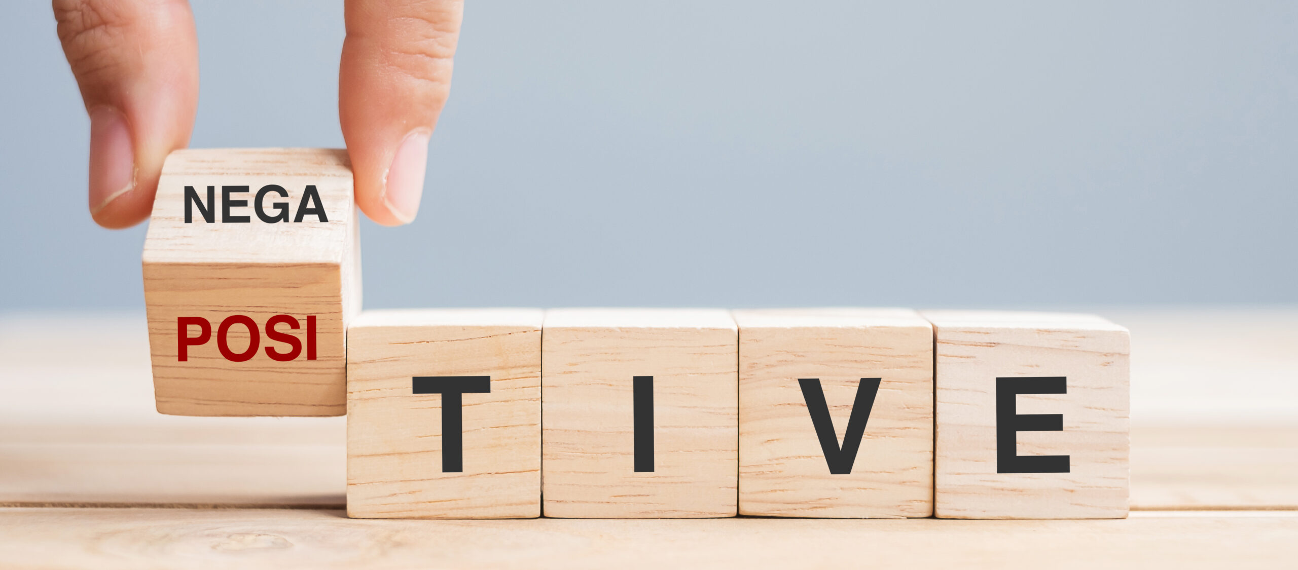 Business man hand holding wooden cube with flip block Negative to Positive word on table background. chance, opportunity, mindset, attitude and Positive thinking concepts