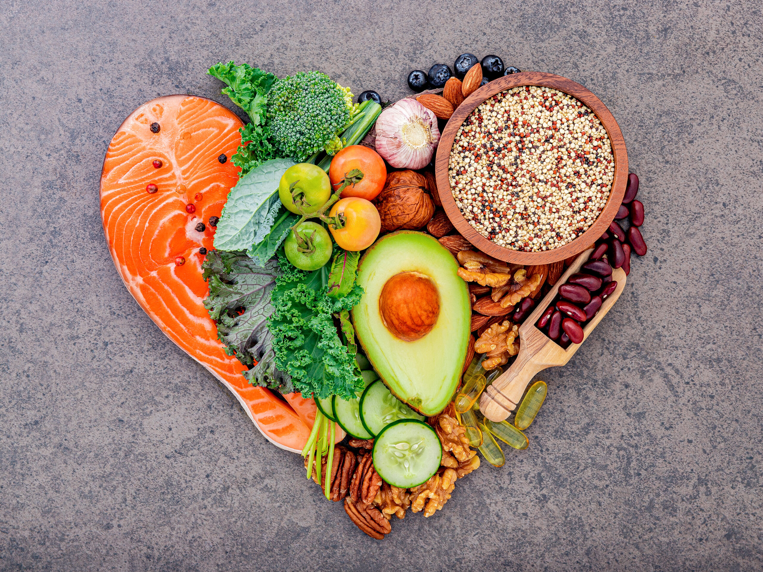 Heart shape of ketogenic low carbs diet concept. Ingredients for healthy foods selection on dark stone background.